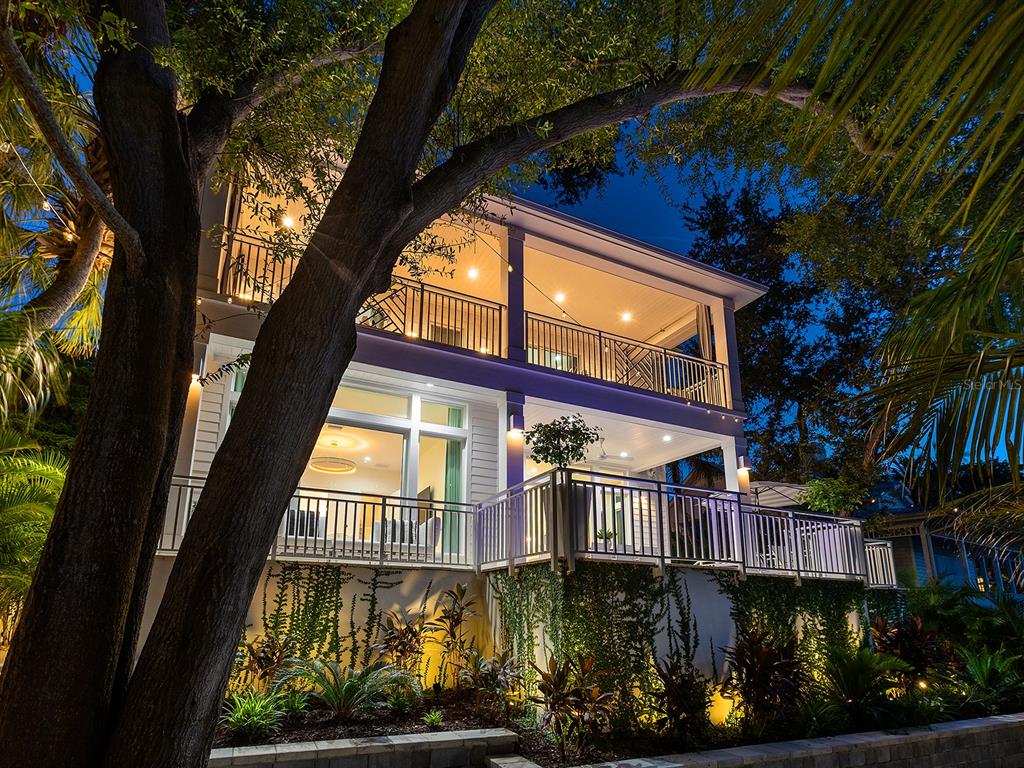 A two-story house with illuminated balconies and landscaped gardens at night — 1621 BAY POINT COURT, SARASOTA, FL