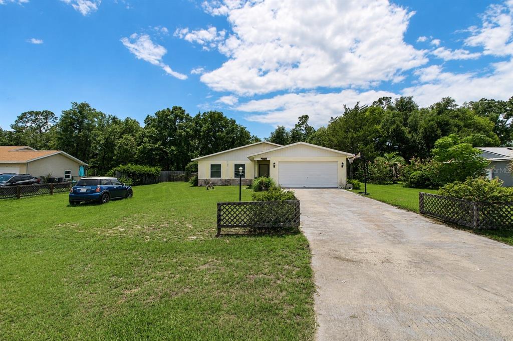 A single-story house with a white garage and a large front lawn under a blue sky — 742 BAHIA CIRCLE, OCALA, FL