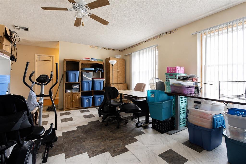 A room with a ceiling fan, tiled floor, exercise equipment, storage bins, and a desk — 742 BAHIA CIRCLE, OCALA, FL