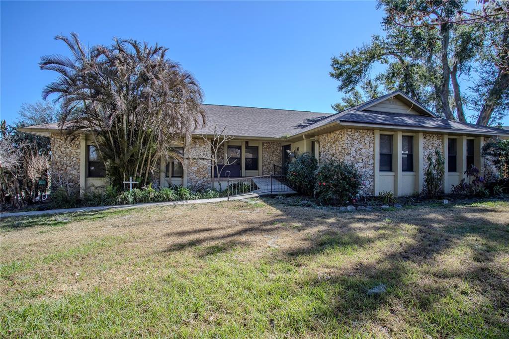 A single-story house with a stone facade and a large palm tree in the yard — 13 HERMOSA DRIVE, EUSTIS, FL
