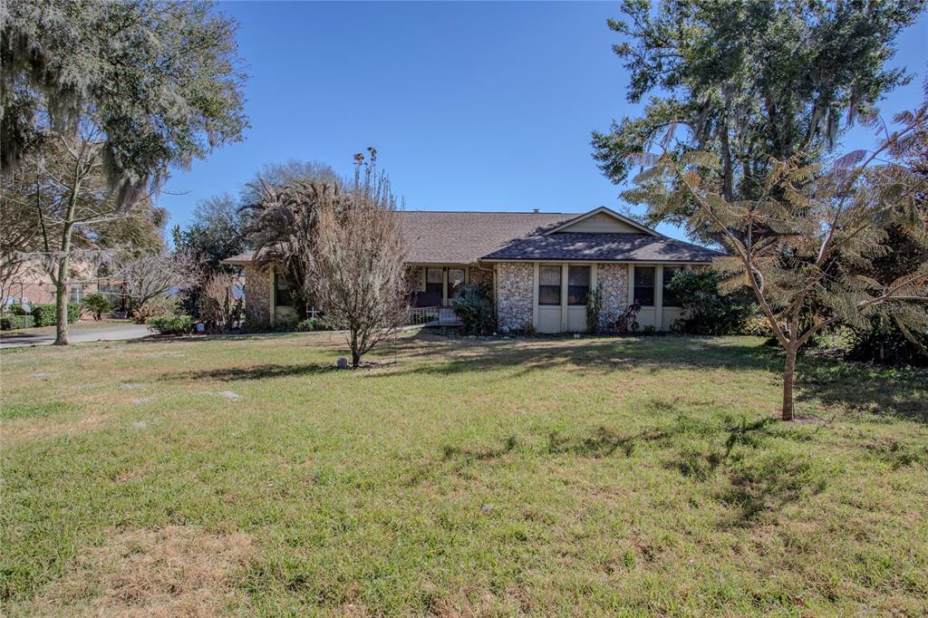 A single-story house with a stone facade and a shingled roof sits on a lawn — 13 HERMOSA DRIVE, EUSTIS, FL