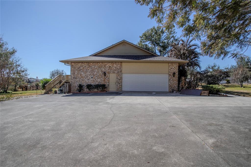 A detached garage with a stone facade and a large concrete driveway — 13 HERMOSA DRIVE, EUSTIS, FL