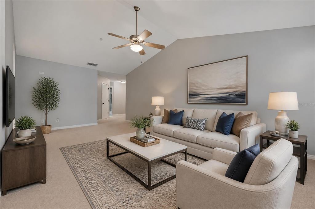 A living room features a vaulted ceiling, a ceiling fan, a sofa, and an armchair — 1010 LOCH VAIL UNIT 23, APOPKA, FL