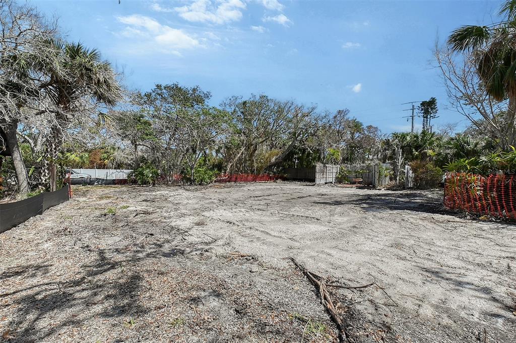 A cleared, sandy residential lot is surrounded by mature trees and orange construction fencing — 8504 HERON LAGOON CIRCLE, SARASOTA, FL