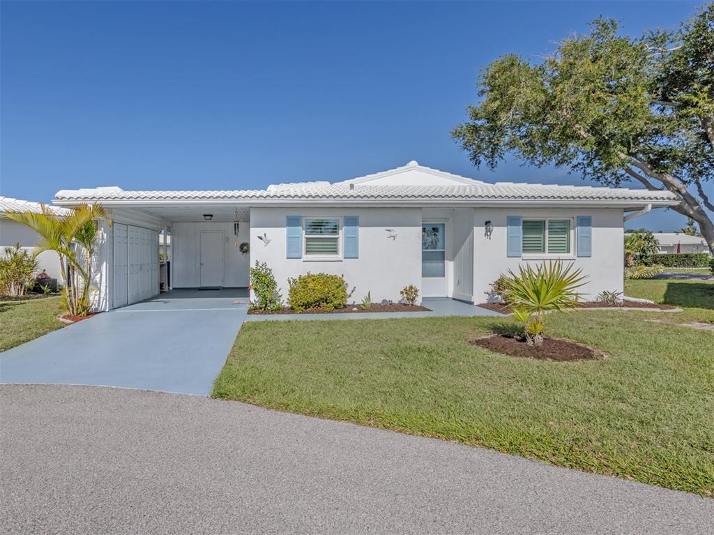 A white single-story house with a blue-painted driveway, carport, and light blue window shutters — 414 CIRCLEWOOD DRIVE UNIT H2, VENICE, FL