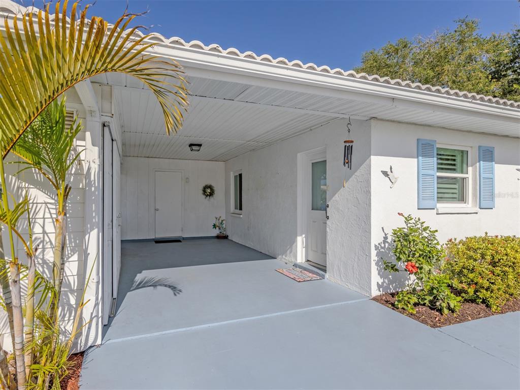 A white house exterior features a covered carport, a front door, and blue shutters — 414 CIRCLEWOOD DRIVE UNIT H2, VENICE, FL