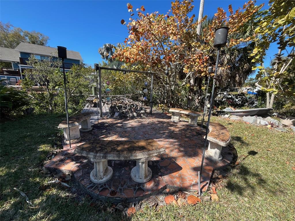 A circular stone patio features three curved benches surrounding a central fire pit area — Lot 96 BLUE JAY CIRCLE, PALM HARBOR, FL
