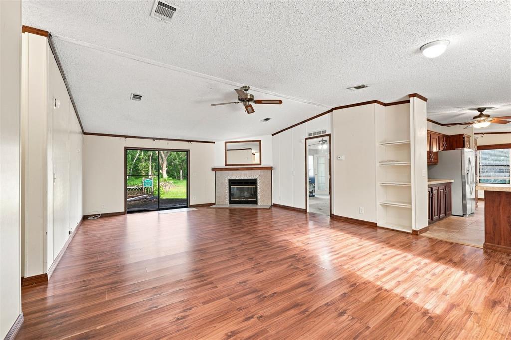 A living room with wood-look flooring, a fireplace, and an adjacent kitchen — 4311 CULBREATH ROAD, BROOKSVILLE, FL