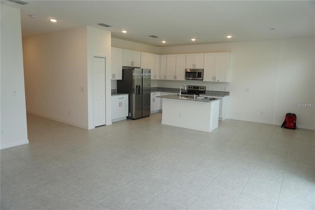 A kitchen with white cabinets, granite countertops, stainless steel appliances, and a central island — 1677 WAY OF PEACE LANE, MASCOTTE, FL