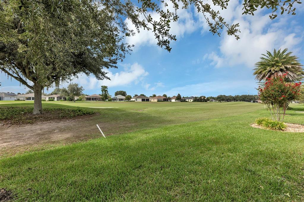 A view of a grassy golf course fairway with houses in the background under blue skies — 27131 ROANOKE DRIVE, LEESBURG, FL
