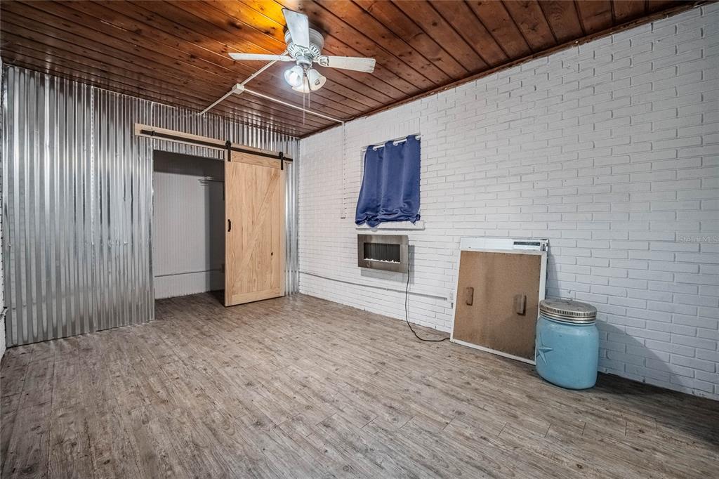 A room with wood-plank ceilings, white brick walls, corrugated metal siding, and a sliding door — 218 MAPLE LANE, FORT MEADE, FL