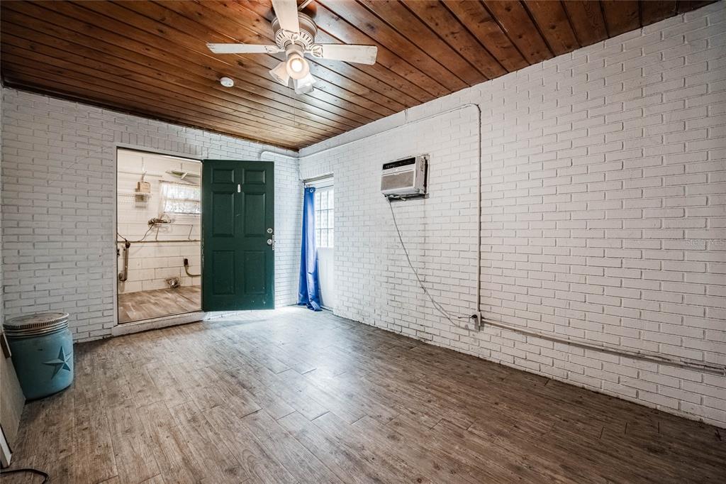 A room with white painted brick walls, a wood-paneled ceiling, and wood-look tile flooring — 218 MAPLE LANE, FORT MEADE, FL