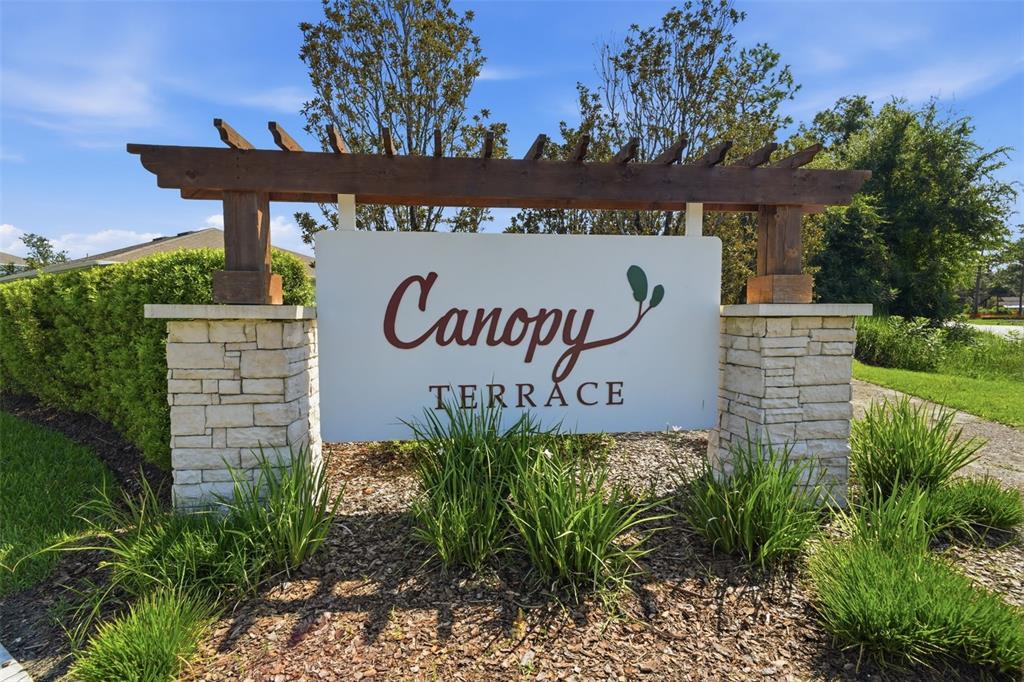A stone and wood monument sign for Canopy Terrace stands in a landscaped garden area — 3545 TREETOP STREET, DELAND, FL