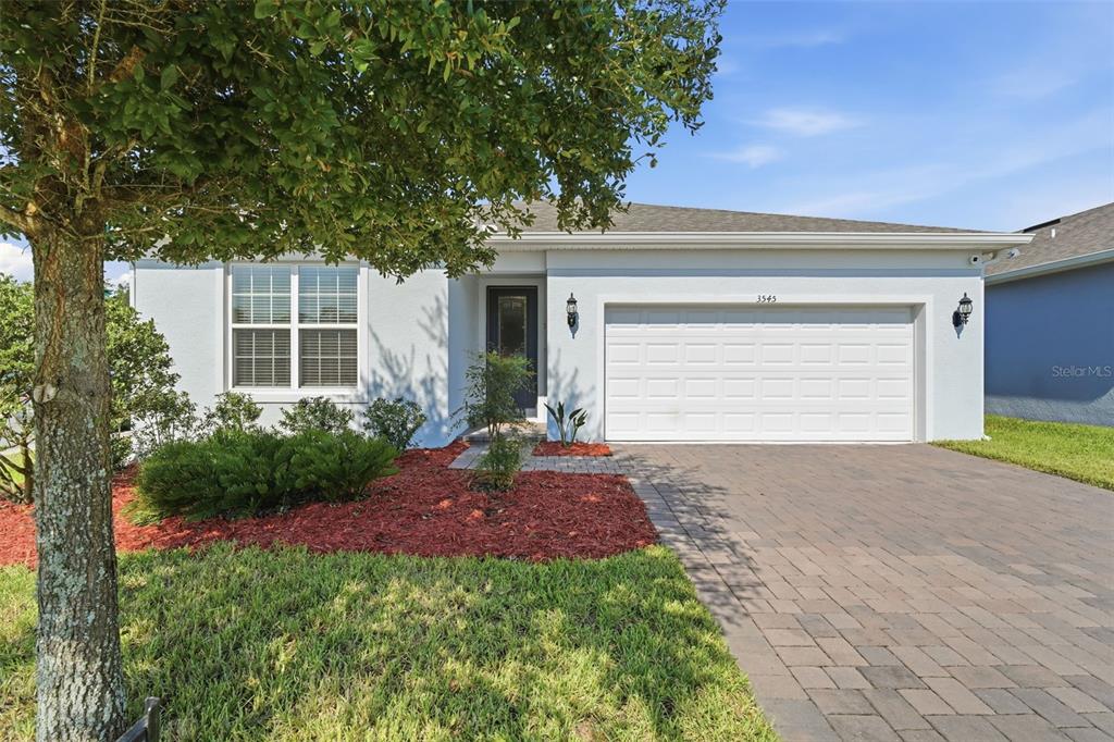A single-story house with a white stucco exterior, a two-car garage, and a paved driveway — 3545 TREETOP STREET, DELAND, FL
