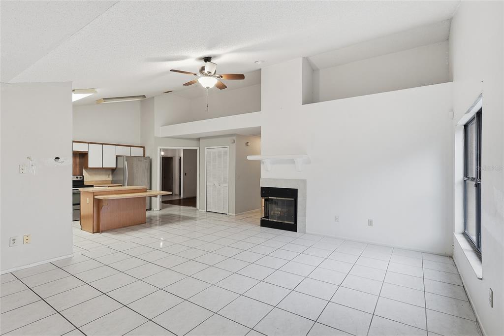 A kitchen with white cabinets and a wooden island opens into a tiled living area — 2939 DANFORTH DRIVE, ORLANDO, FL