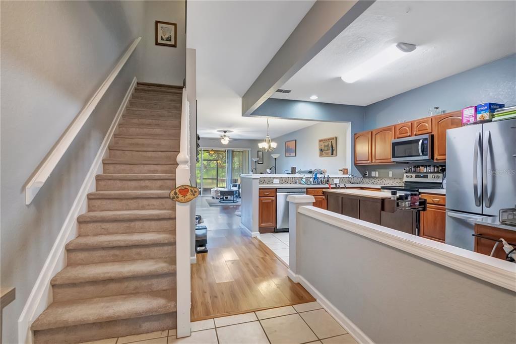 A carpeted staircase leads to an open-concept kitchen and living area with wood flooring — 612 SHROPSHIRE LOOP, SANFORD, FL