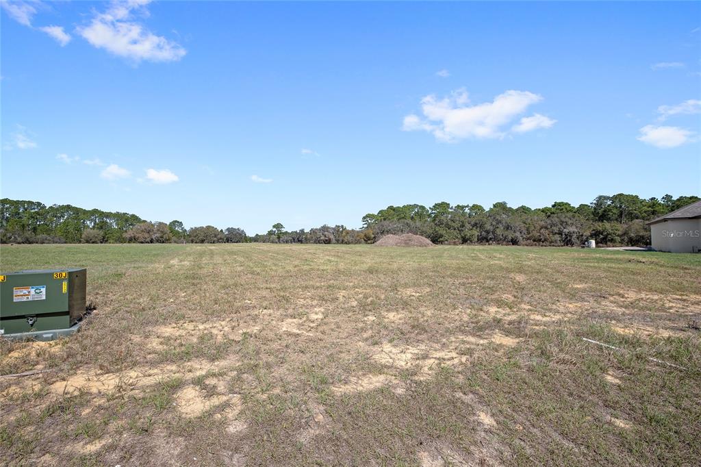A large, flat, grassy vacant lot under a blue sky with scattered clouds — 38361 LAKE MEADOW COURT, UMATILLA, FL