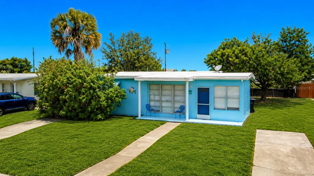 A light blue single-story house features a covered front porch and a large palm tree — 8594 BUMFORD AVENUE, NORTH PORT, FL