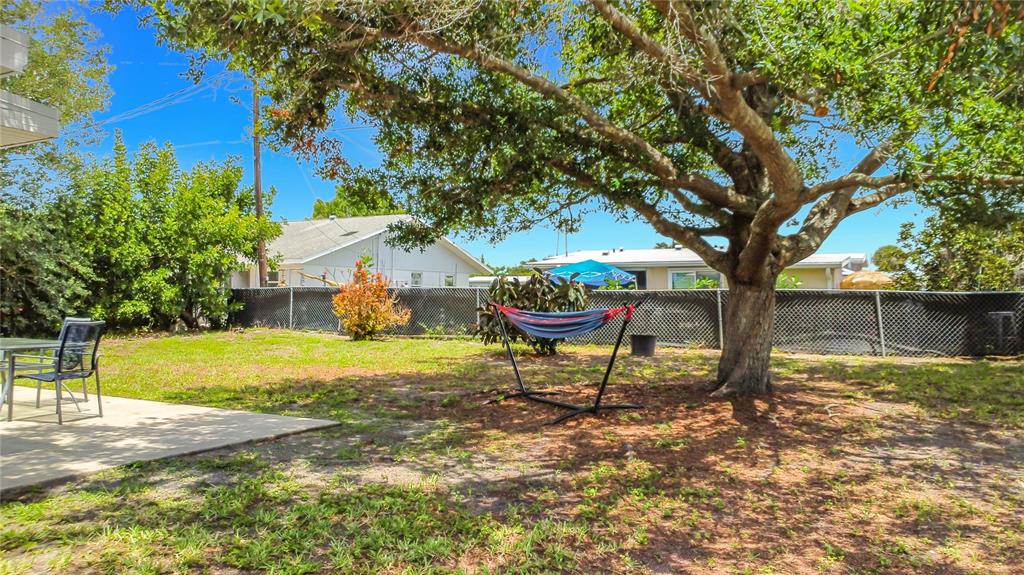 A backyard features a hammock under a large tree, a patio, and a chain-link fence — 8594 BUMFORD AVENUE, NORTH PORT, FL