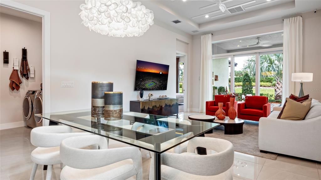 A dining area with a glass table and white chairs opens into a living room — 423 VERONA WAY, LADY LAKE, FL