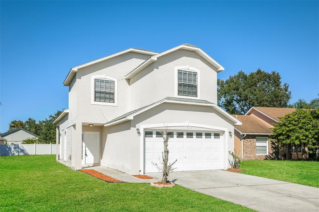 A two-story house with a beige stucco exterior, a two-car garage, and a front lawn — 11943 BLACKHEATH CIRCLE, ORLANDO, FL