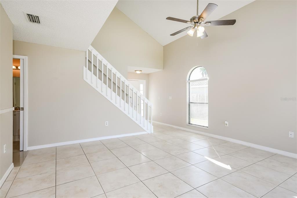 An open living room features tile flooring, a vaulted ceiling, a ceiling fan, and stairs — 11943 BLACKHEATH CIRCLE, ORLANDO, FL