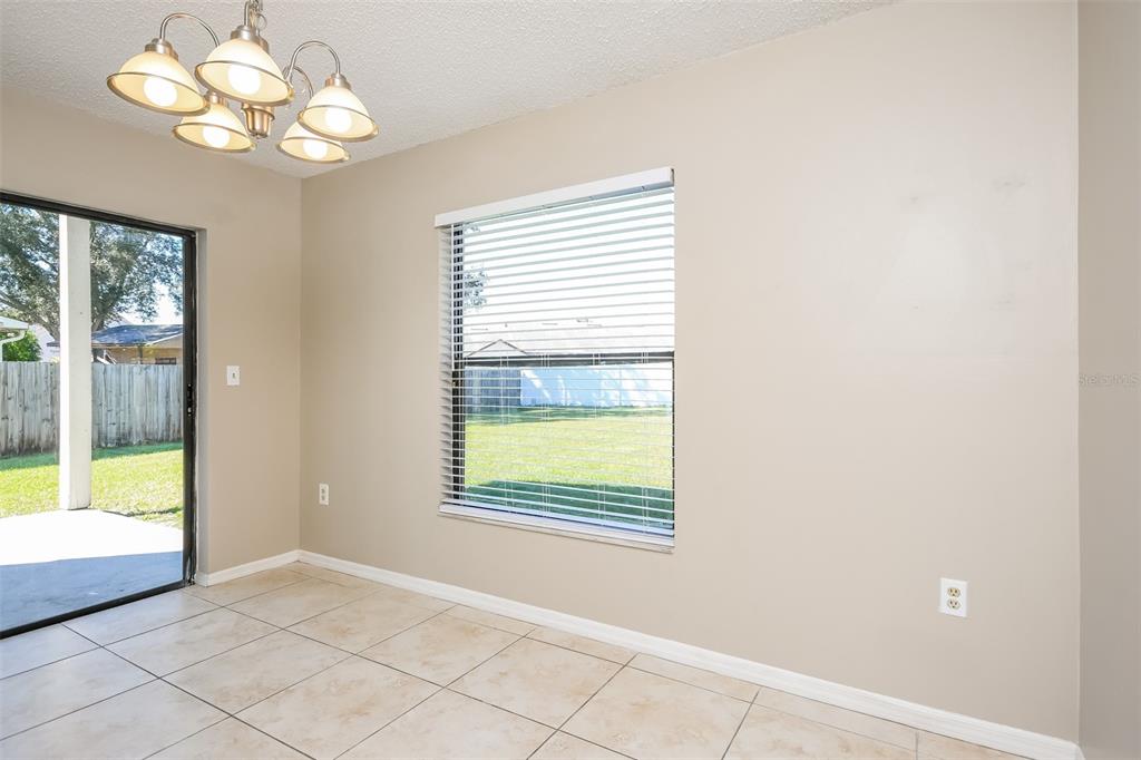 A dining area with tile flooring, a light fixture, a large window, and sliding glass doors — 11943 BLACKHEATH CIRCLE, ORLANDO, FL