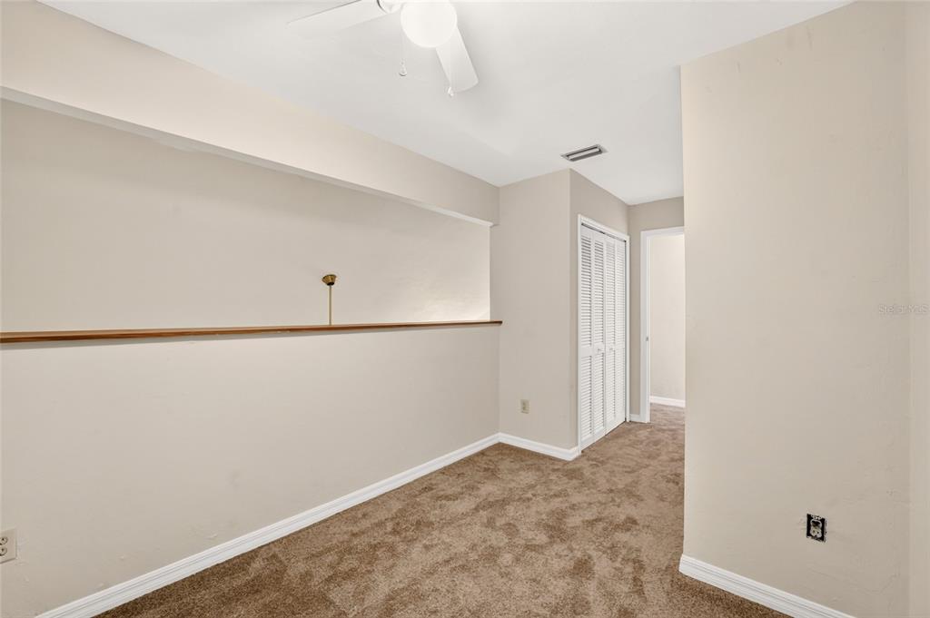 An empty room with brown carpet, a ceiling fan, a wooden ledge, and a closet — 924 SW 57TH DRIVE, GAINESVILLE, FL