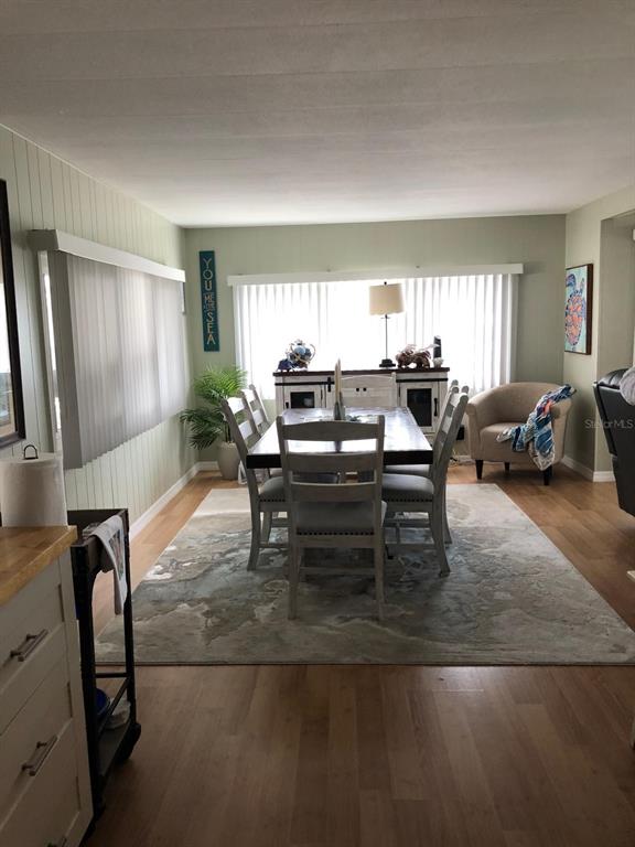 A dining room features a wooden table with six chairs, a rug, and vertical blinds — 1100 BELCHER ROAD S UNIT 18, LARGO, FL