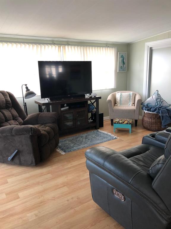 A living room features a television on a stand, two recliners, and a small armchair — 1100 BELCHER ROAD S UNIT 18, LARGO, FL
