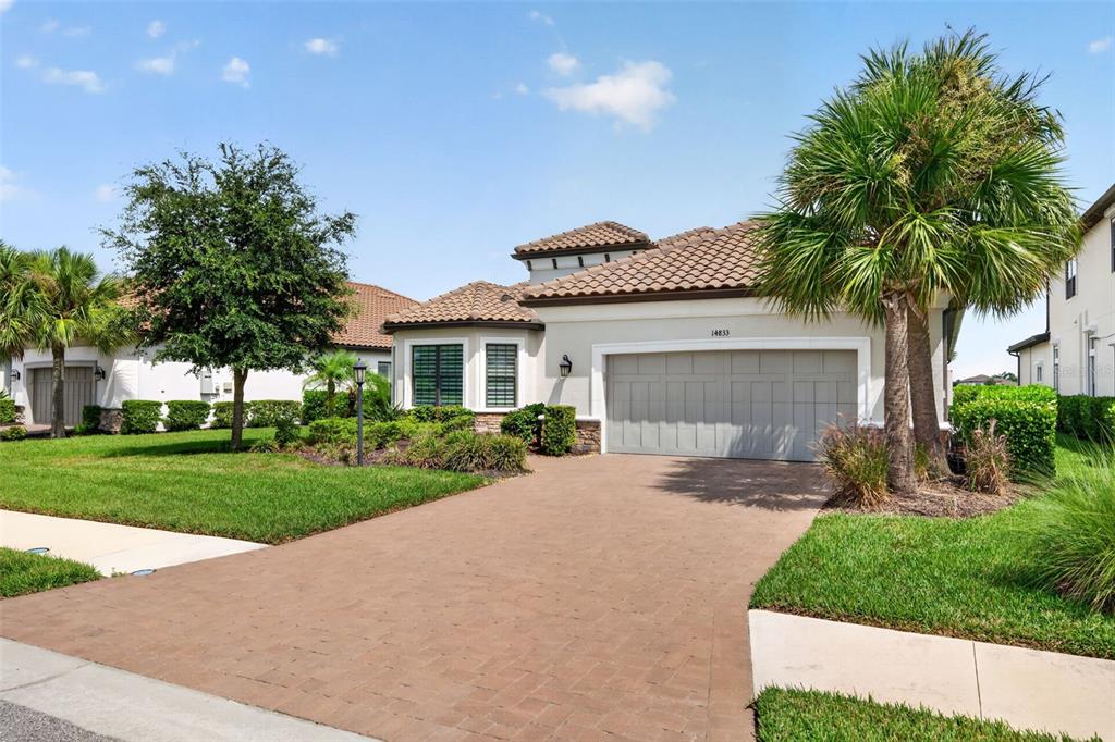 A single-story house with a paved driveway, a two-car garage, and surrounding palm trees — 14833 MONTELLO WAY, BRADENTON, FL