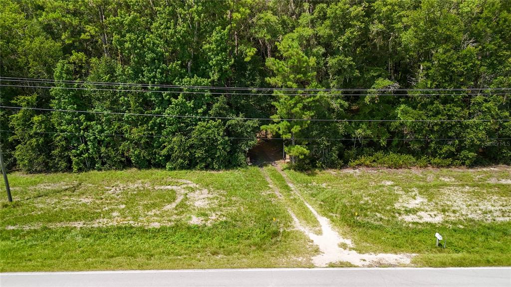 An aerial view shows a dirt driveway leading from a paved road into a wooded area — 7922 SW COUNTY ROAD 346, ARCHER, FL