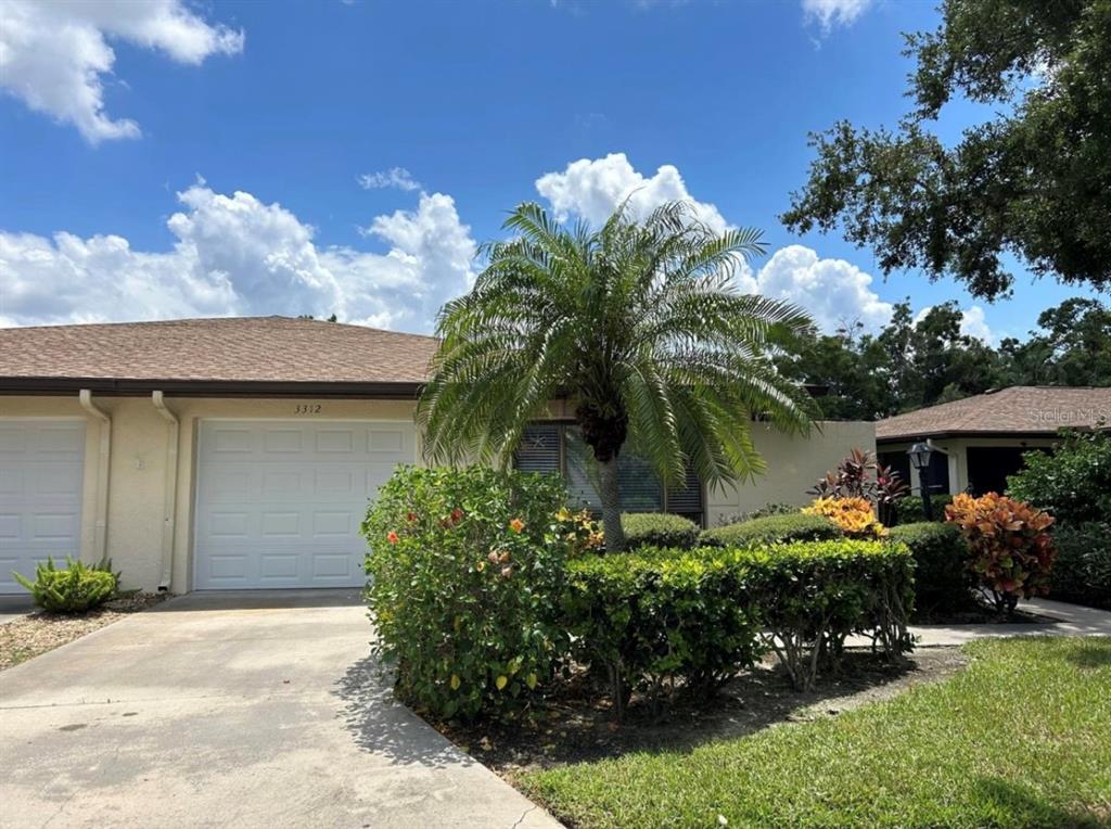 A single-story home with a white garage door, a palm tree, and manicured landscaping — 3312 VIVIENDA BOULEVARD, BRADENTON, FL