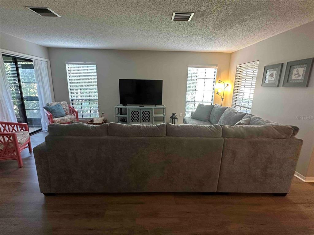 A living room features a large gray sectional sofa, a television on a stand, and wood-look flooring — 3312 VIVIENDA BOULEVARD, BRADENTON, FL