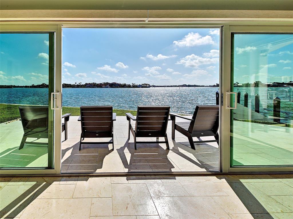 Three dark chairs sit on a stone patio overlooking a body of water — 885 WHITE CAP CIRCLE UNIT 34, VENICE, FL