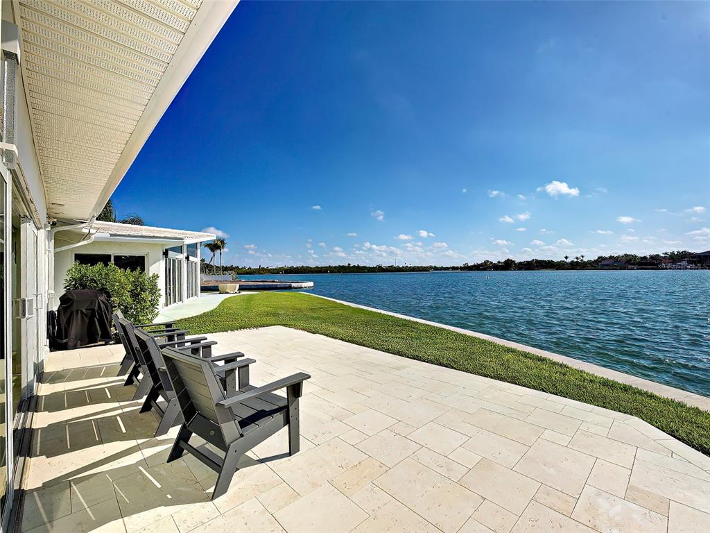 A paved patio with chairs overlooks a grassy lawn and a large body of water — 885 WHITE CAP CIRCLE UNIT 34, VENICE, FL