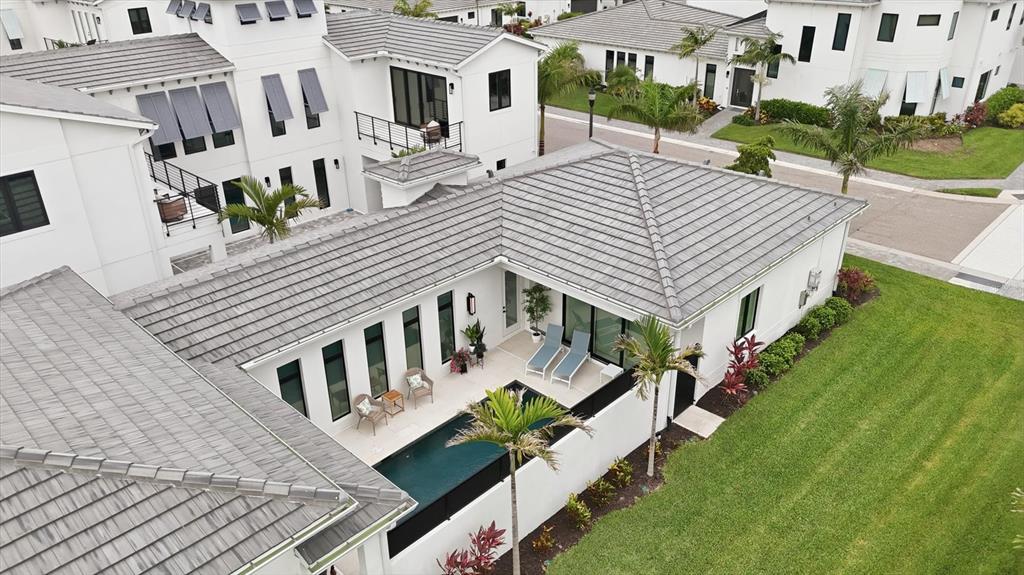 An aerial view shows a white house with a gray tile roof and a courtyard pool — 5931 CAT CLAW LANE, BRADENTON, FL