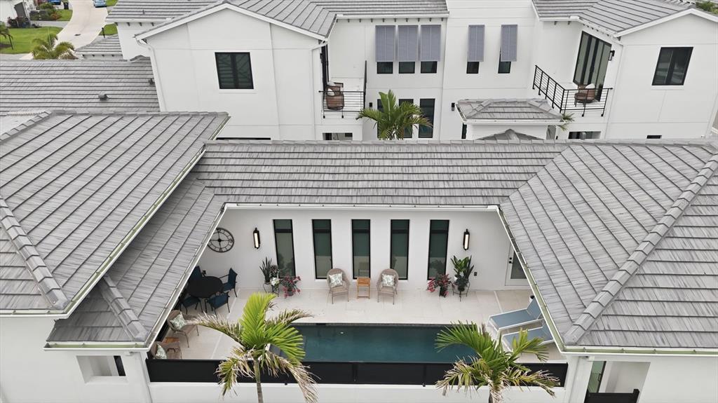 An aerial view shows a white house with a gray tile roof and a courtyard pool — 5931 CAT CLAW LANE, BRADENTON, FL