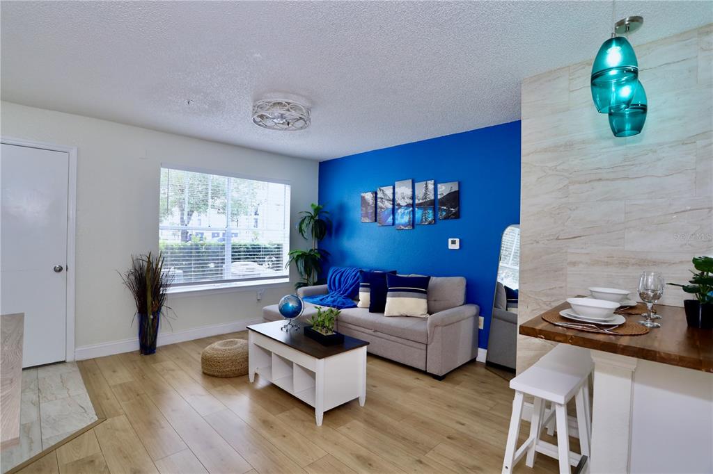 A living room features a blue accent wall, light wood flooring, and a dining area — 2207 ANTIGUA PLACE UNIT 717, KISSIMMEE, FL