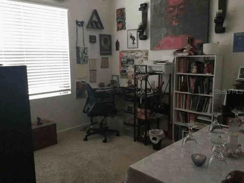 A home office features a desk, an office chair, a bookshelf, and wall art — 1661 PALATKA ROAD SE, PALM BAY, FL