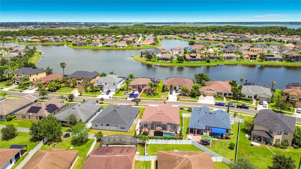 An aerial view of a suburban neighborhood featuring houses with pools surrounding a large lake — 3034 BOATING BOULEVARD, KISSIMMEE, FL