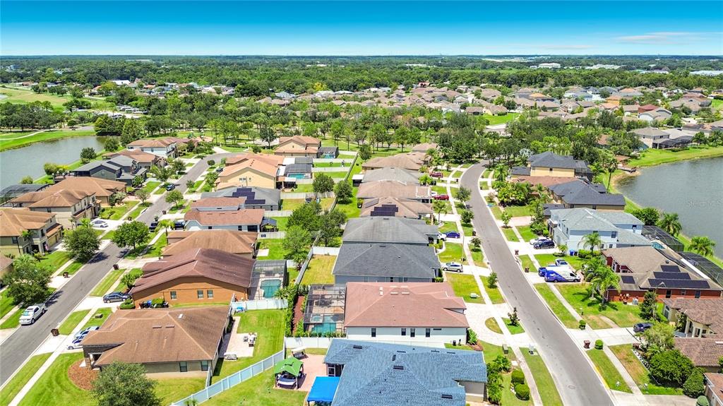 An aerial view shows a suburban neighborhood with houses, swimming pools, and a nearby lake — 3034 BOATING BOULEVARD, KISSIMMEE, FL