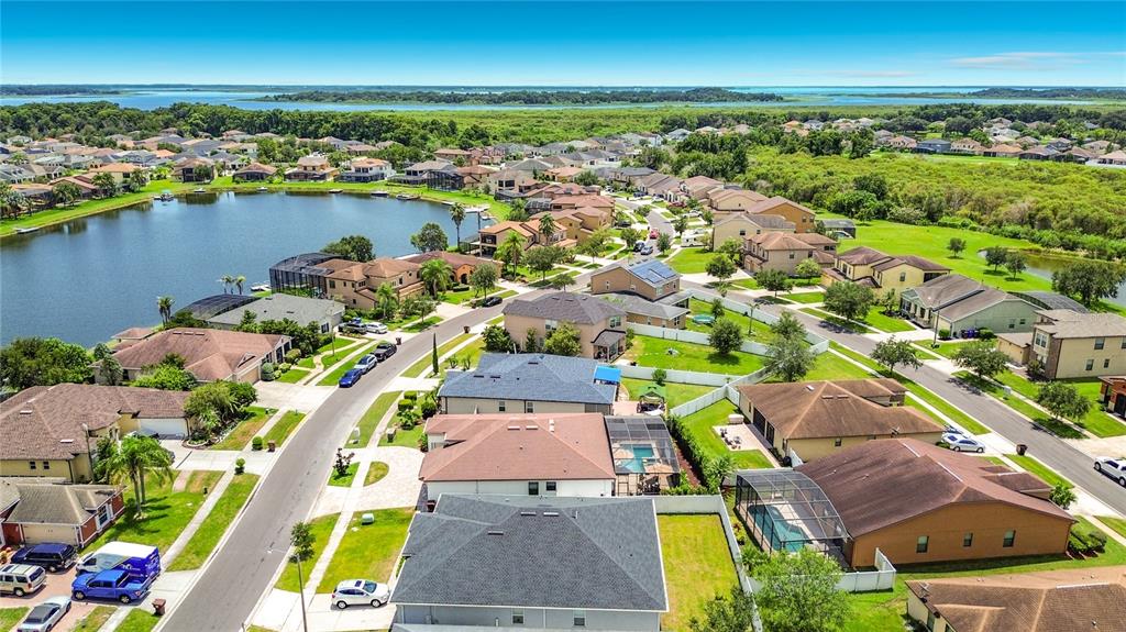 An aerial view shows a suburban neighborhood with houses, a lake, and green spaces — 3034 BOATING BOULEVARD, KISSIMMEE, FL