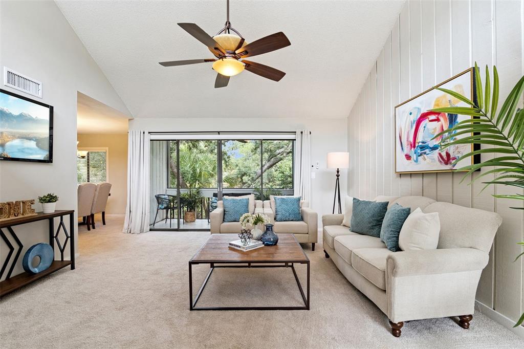 A living room features a vaulted ceiling, a ceiling fan, a sofa, and sliding glass doors — 203 CROWN OAKS WAY UNIT 203, LONGWOOD, FL