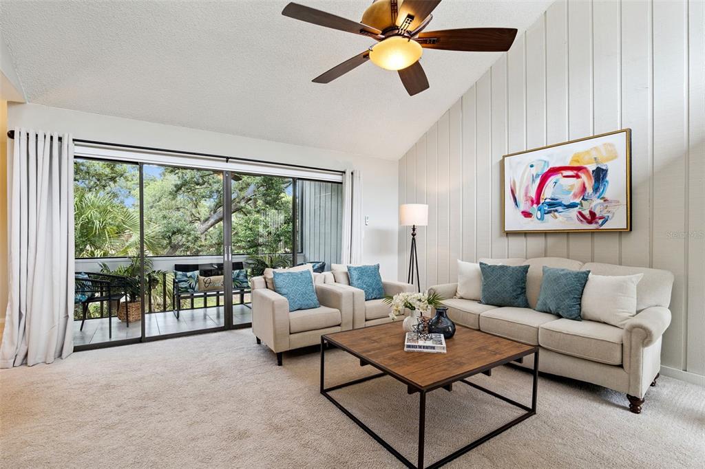 A living room with a vaulted ceiling, beige sofa, two armchairs, and a sliding glass door — 203 CROWN OAKS WAY UNIT 203, LONGWOOD, FL