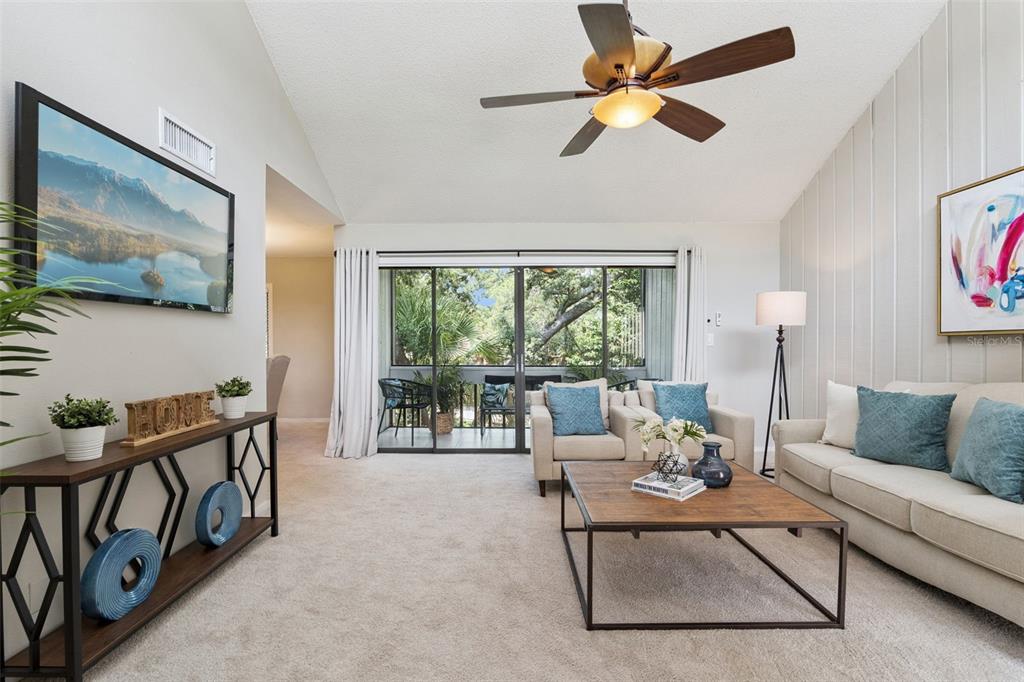 A living room with a vaulted ceiling, ceiling fan, sliding glass doors, and neutral furniture — 203 CROWN OAKS WAY UNIT 203, LONGWOOD, FL
