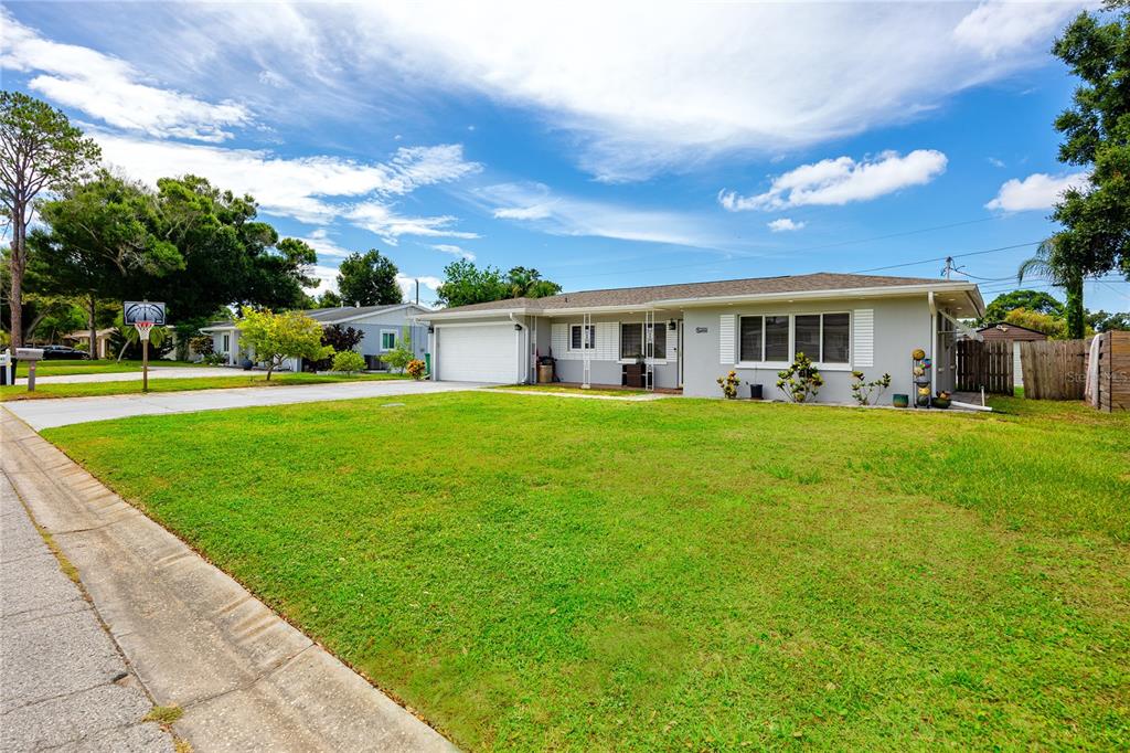A single-story house with a gray exterior, a white garage door, and a large lawn — 1833 HUNT LANE, CLEARWATER, FL
