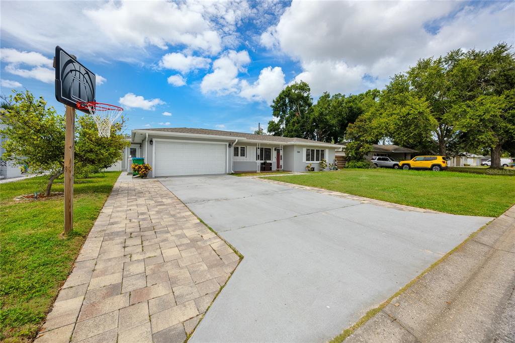 A single-story house with a concrete driveway, a basketball hoop, and a grassy front yard — 1833 HUNT LANE, CLEARWATER, FL
