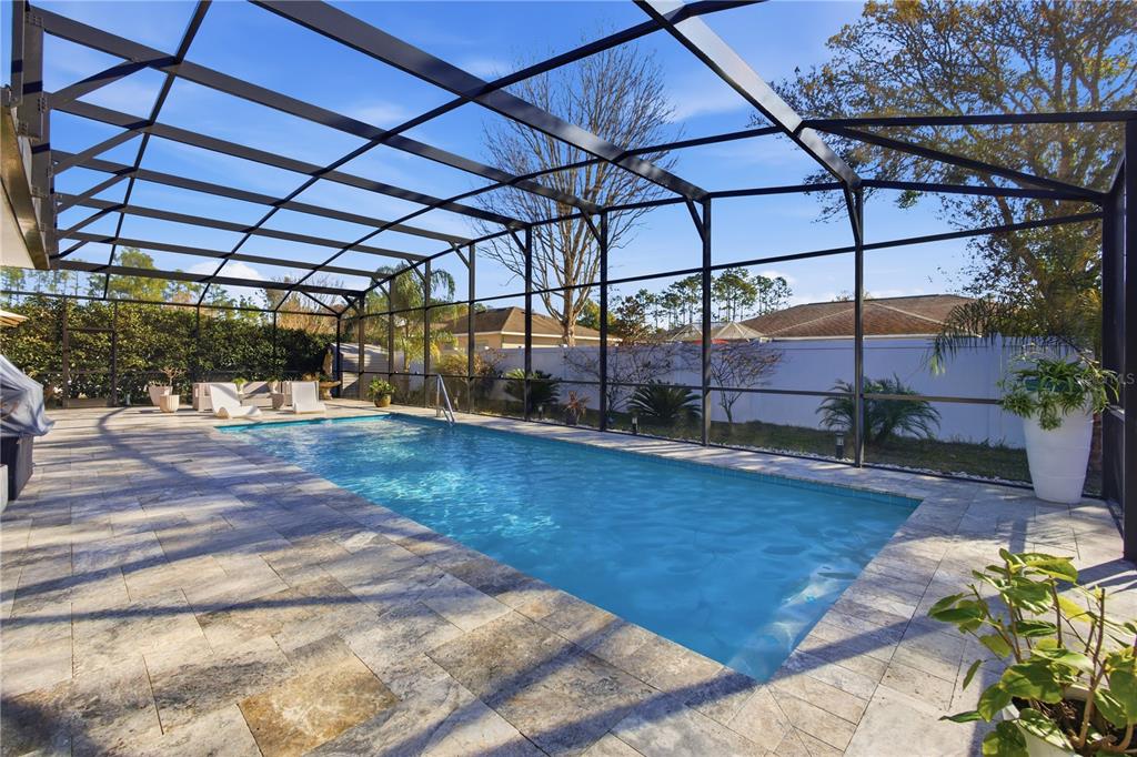 A rectangular swimming pool with a stone deck is enclosed by a black metal screen cage — 35 EDGELY LANE, PALM COAST, FL