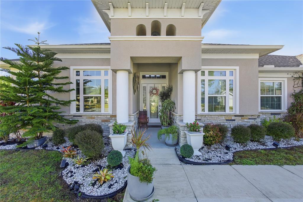 The exterior of a house features a covered entryway with white columns and stone accents — 35 EDGELY LANE, PALM COAST, FL